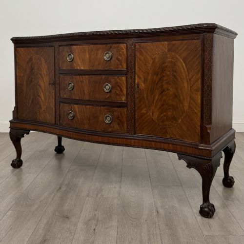 fig 2. An Edwardian mahogany sideboard with three central drawers flanked by cupboard doors featuring oval mahogany veneers and carved cabriole legs terminating in ball-and-claw feet.