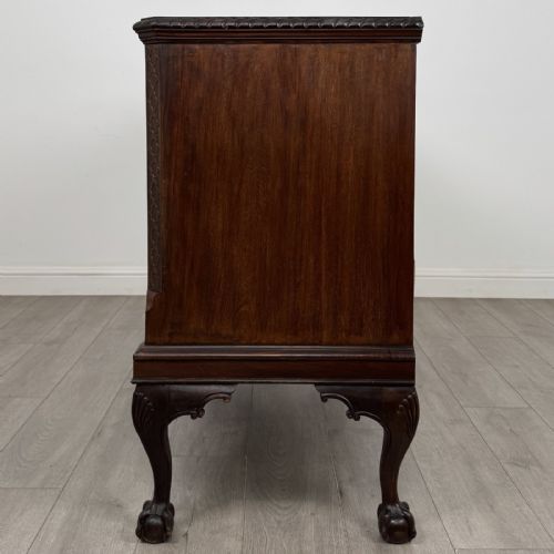 fig 3. An Edwardian mahogany sideboard with three central drawers flanked by cupboard doors featuring oval mahogany veneers and carved cabriole legs terminating in ball-and-claw feet.