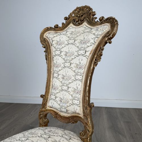 fig 8. An antique 19th-century French giltwood hall chair featuring a high upholstered backrest, ornate scroll carving, cabriole legs, and brass castors.