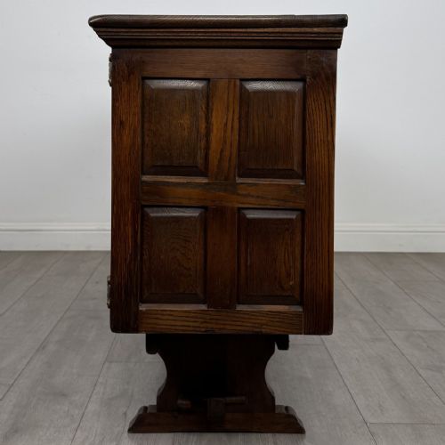 fig 3. A large dark oak sideboard featuring carved panel doors, central drawers, decorative metal hinges, and a stretcher base.