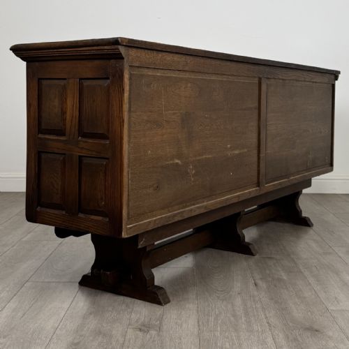 fig 4. A large dark oak sideboard featuring carved panel doors, central drawers, decorative metal hinges, and a stretcher base.