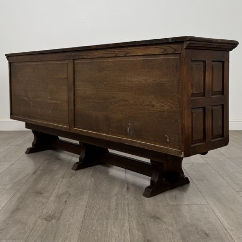 fig 6. A large dark oak sideboard featuring carved panel doors, central drawers, decorative metal hinges, and a stretcher base.