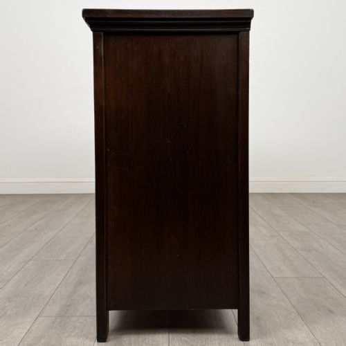 fig 3. A dark oak sideboard featuring three top drawers with metal ring pulls above three carved panel cupboard doors.