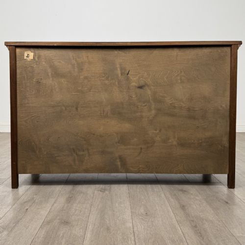 fig 5. A dark oak sideboard featuring three top drawers with metal ring pulls above three carved panel cupboard doors.