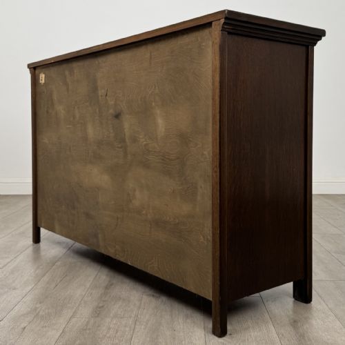fig 6. A dark oak sideboard featuring three top drawers with metal ring pulls above three carved panel cupboard doors.