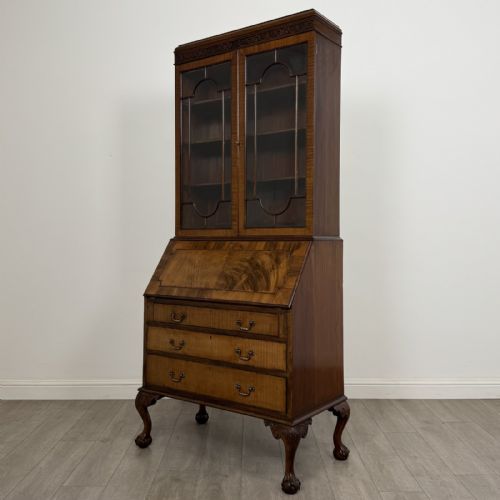 fig 2. An Edwardian walnut bureau bookcase with a glazed upper cabinet, slant-front writing desk, three drawers, and cabriole legs on claw and ball feet.
