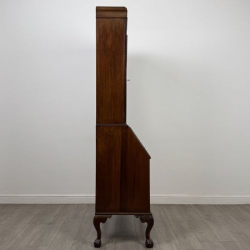 fig 7. An Edwardian walnut bureau bookcase with a glazed upper cabinet, slant-front writing desk, three drawers, and cabriole legs on claw and ball feet.