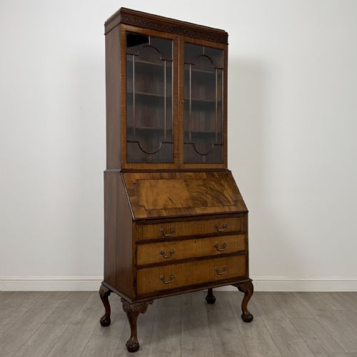fig 8. An Edwardian walnut bureau bookcase with a glazed upper cabinet, slant-front writing desk, three drawers, and cabriole legs on claw and ball feet.
