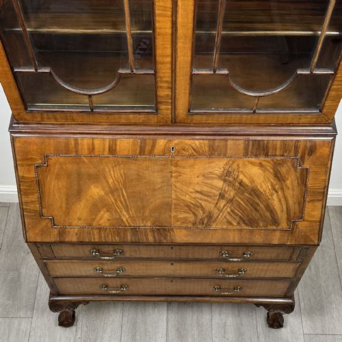 fig 9. An Edwardian walnut bureau bookcase with a glazed upper cabinet, slant-front writing desk, three drawers, and cabriole legs on claw and ball feet.