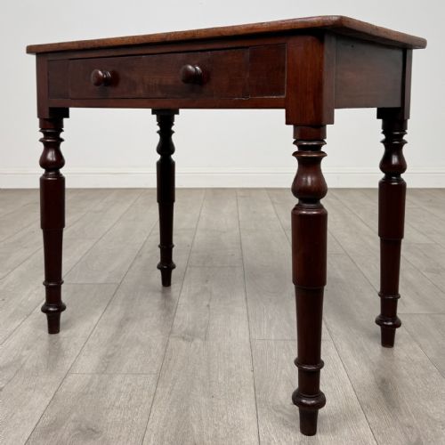 fig 1. A Victorian mahogany writing table featuring a rectangular top, a single drawer with two wooden knobs, and four turned legs.