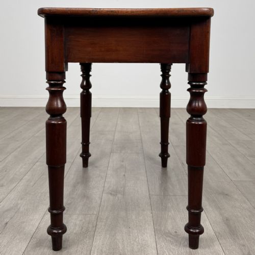 fig 2. A Victorian mahogany writing table featuring a rectangular top, a single drawer with two wooden knobs, and four turned legs.