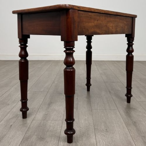 fig 3. A Victorian mahogany writing table featuring a rectangular top, a single drawer with two wooden knobs, and four turned legs.