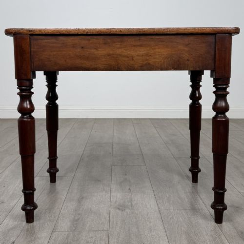 fig 4. A Victorian mahogany writing table featuring a rectangular top, a single drawer with two wooden knobs, and four turned legs.