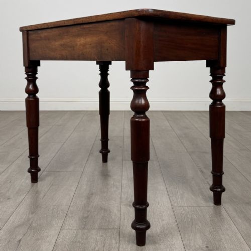 fig 5. A Victorian mahogany writing table featuring a rectangular top, a single drawer with two wooden knobs, and four turned legs.