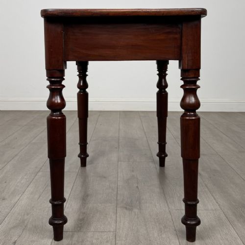 fig 6. A Victorian mahogany writing table featuring a rectangular top, a single drawer with two wooden knobs, and four turned legs.