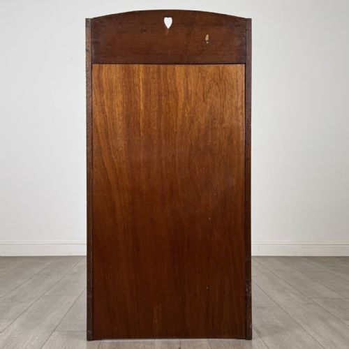 fig 5. An Arts and Crafts golden oak bureau with a heart cutout on the top gallery back, a fall-front writing surface with drop handles, and two open bookshelves underneath.