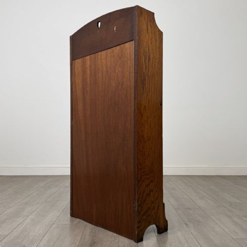 fig 6. An Arts and Crafts golden oak bureau with a heart cutout on the top gallery back, a fall-front writing surface with drop handles, and two open bookshelves underneath.