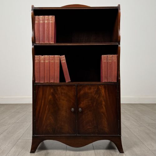 fig 1. An antique mahogany open bookcase featuring a shaped raised gallery top, two upper shelf spaces, and a lower two-door cabinet with flame mahogany veneered panels.