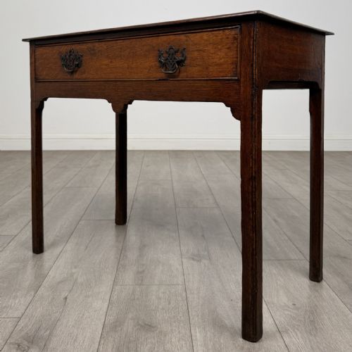 fig 1. An 18th-century Georgian dark oak side table featuring a single drawer with pierced brass handles and straight square legs.