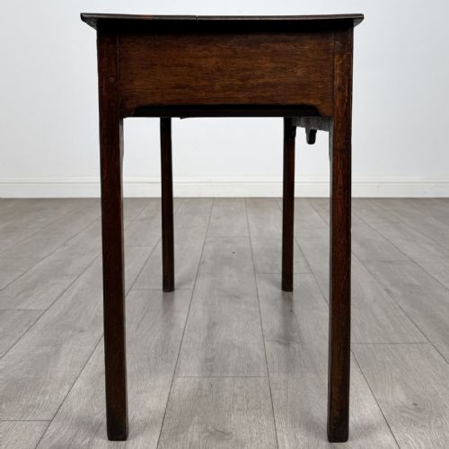 fig 6. An 18th-century Georgian dark oak side table featuring a single drawer with pierced brass handles and straight square legs.