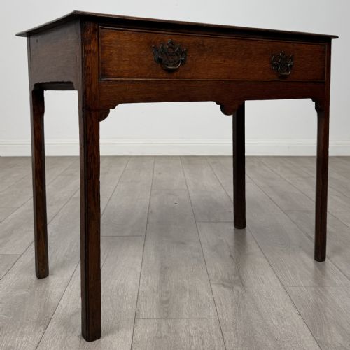 fig 7. An 18th-century Georgian dark oak side table featuring a single drawer with pierced brass handles and straight square legs.