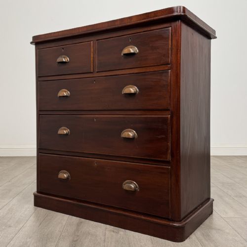 fig 1. A Victorian mahogany chest of drawers featuring a two-over-three drawer configuration, brass cup handles, and a plinth base.
