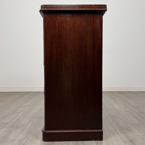 fig 2. A Victorian mahogany chest of drawers featuring a two-over-three drawer configuration, brass cup handles, and a plinth base.