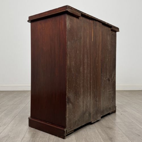 fig 3. A Victorian mahogany chest of drawers featuring a two-over-three drawer configuration, brass cup handles, and a plinth base.