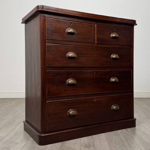fig 6. A Victorian mahogany chest of drawers featuring a two-over-three drawer configuration, brass cup handles, and a plinth base.