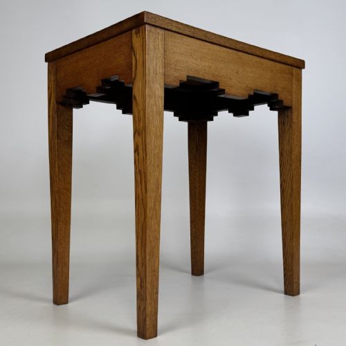 fig 1. A tall, slender Arts and Crafts golden oak side table featuring tapered square legs and a notched, stepped apron.