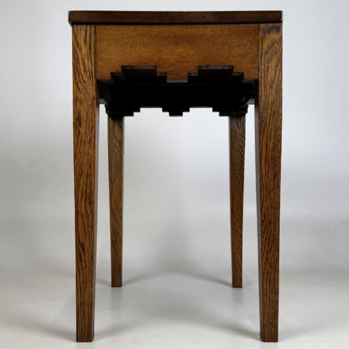 fig 4. A tall, slender Arts and Crafts golden oak side table featuring tapered square legs and a notched, stepped apron.