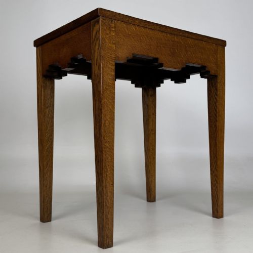 fig 5. A tall, slender Arts and Crafts golden oak side table featuring tapered square legs and a notched, stepped apron.