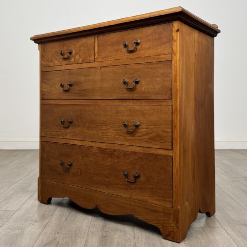 fig 1. An antique ash chest of drawers featuring a two-over-three drawer configuration with drop handles and a shaped lower apron.