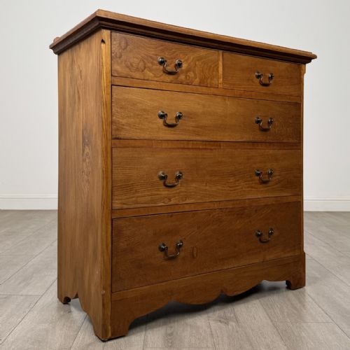 fig 7. An antique ash chest of drawers featuring a two-over-three drawer configuration with drop handles and a shaped lower apron.