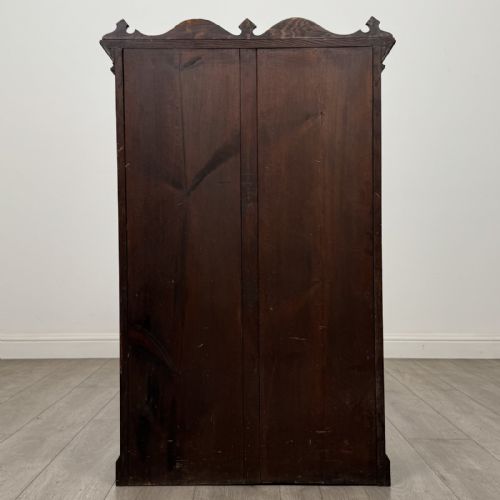 fig 5. A dark oak Victorian display cabinet featuring a dentil cornice, glazed upper doors, two drawers with brass handles, and panelled lower cupboard doors.