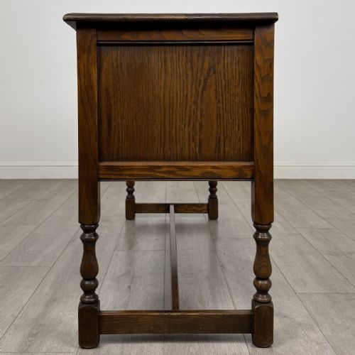 fig 2. An antique dark oak writing desk featuring five carved drawers with metal drop handles, turned legs, and lower stretchers.