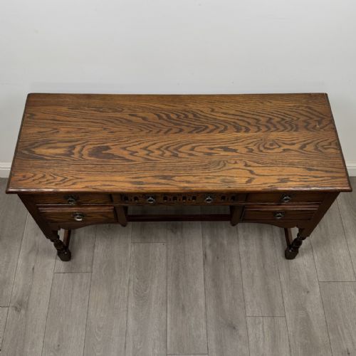 fig 8. An antique dark oak writing desk featuring five carved drawers with metal drop handles, turned legs, and lower stretchers.