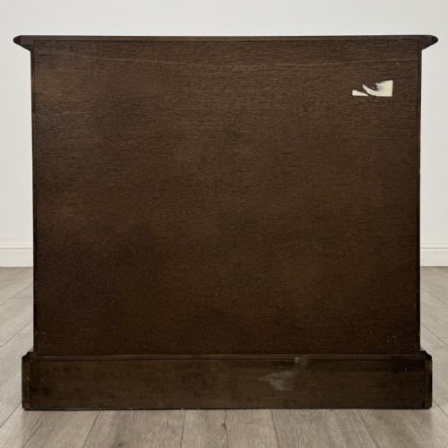 fig 4. A dark brown oak storage cupboard featuring two top drawers above twin doors with carved linenfold panels and brass handles.