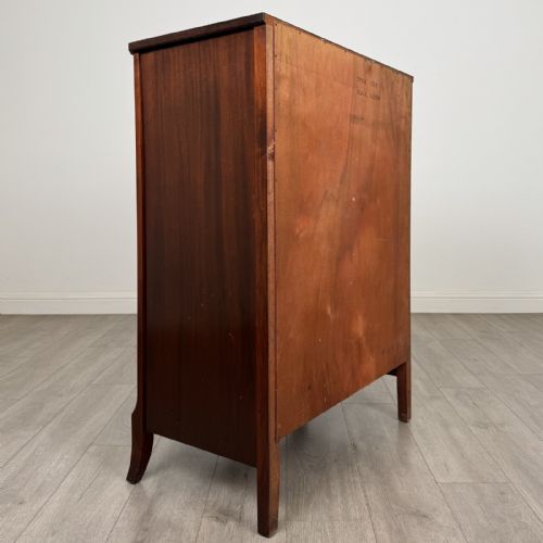 fig 3. An antique mahogany chest of drawers with a bowfront shape, brass oval handles, and reeded side columns.