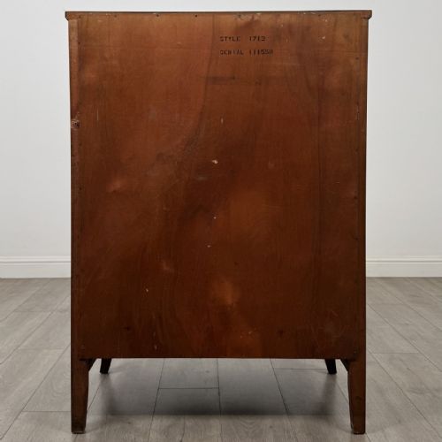 fig 4. An antique mahogany chest of drawers with a bowfront shape, brass oval handles, and reeded side columns.