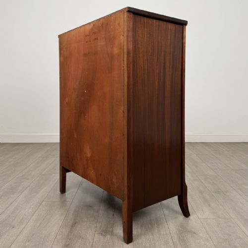 fig 5. An antique mahogany chest of drawers with a bowfront shape, brass oval handles, and reeded side columns.