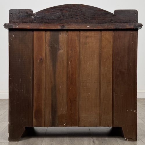 fig 5. An Edwardian dark oak cupboard featuring a raised carved gallery, two top drawers with brass drop handles, and two panelled doors decorated with carved central cartouches.