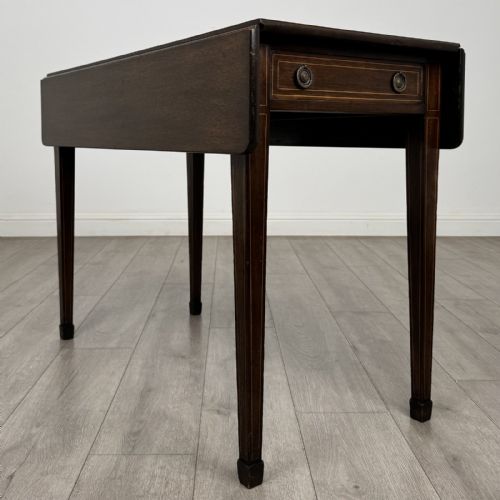 fig 2. A dark brown mahogany Pembroke table featuring two drop flaps, a front drawer with boxwood line inlay, two brass ring handles, and square tapered legs ending in spade feet.