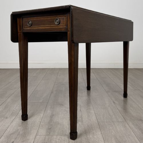 fig 5. A dark brown mahogany Pembroke table featuring two drop flaps, a front drawer with boxwood line inlay, two brass ring handles, and square tapered legs ending in spade feet.