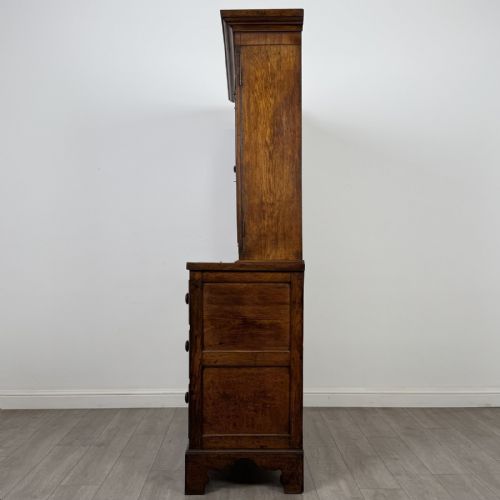 fig 4. An 18th-century Georgian golden oak glazed bookcase resting upon a chest of three long drawers with turned wooden handles and shaped bracket feet.