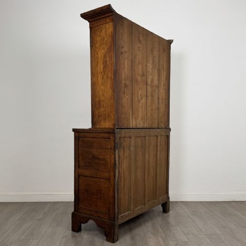 fig 5. An 18th-century Georgian golden oak glazed bookcase resting upon a chest of three long drawers with turned wooden handles and shaped bracket feet.