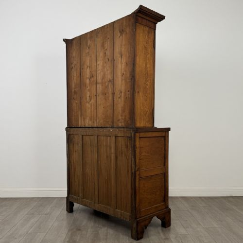 fig 7. An 18th-century Georgian golden oak glazed bookcase resting upon a chest of three long drawers with turned wooden handles and shaped bracket feet.