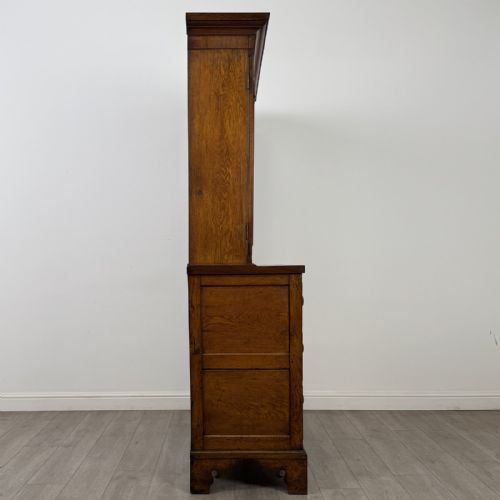 fig 8. An 18th-century Georgian golden oak glazed bookcase resting upon a chest of three long drawers with turned wooden handles and shaped bracket feet.