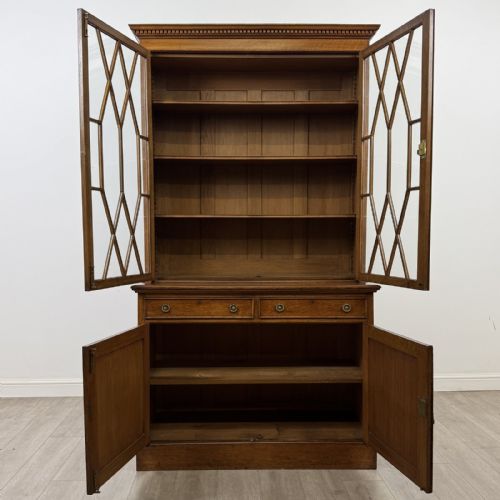 fig 2. A Victorian golden oak two-part glazed bookcase featuring geometric astragal glazing, a dentil cornice, two drawers, and a panelled base cupboard.