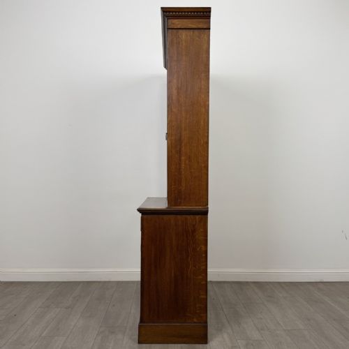 fig 4. A Victorian golden oak two-part glazed bookcase featuring geometric astragal glazing, a dentil cornice, two drawers, and a panelled base cupboard.